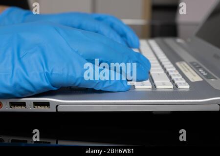 gloved hands typing on computer keyboard Stock Photo
