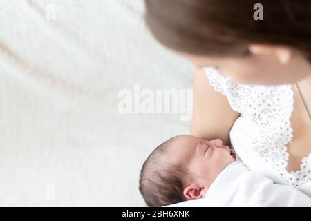 motherhood, infancy, childhood, family, care, medicine, sleep, health, maternity concept - portrait of mom with newborn baby wrapped in diaper on Stock Photo
