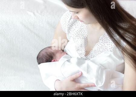 motherhood, infancy, childhood, family, care, medicine, sleep, health, maternity concept - portrait of mom with newborn baby wrapped in diaper on Stock Photo