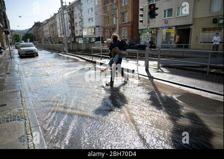 Stuttgart, Germany. 24th Apr, 2020. A man carries a woman on his shoulders across a road flooded due to a broken water pipe. Credit: Marijan Murat/dpa/Alamy Live News Stock Photo
