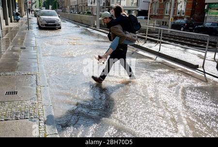 Stuttgart, Germany. 24th Apr, 2020. A man carries a woman on his shoulders across a road flooded by a broken water pipe. Credit: Marijan Murat/dpa/Alamy Live News Stock Photo