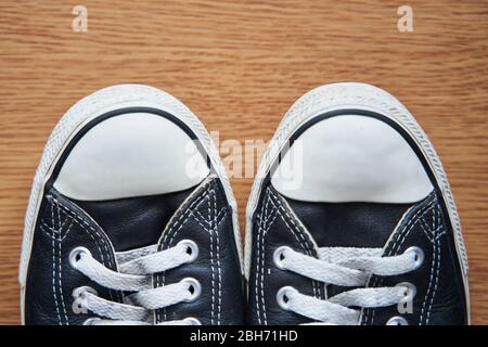 Black leather sneakers on a wooden background.  Stock Photo