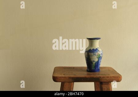 Vintage empty ceramic vase with chinese landscape painting placed on vintage wooden stool, chinese painting is one of the oldest art in the world know Stock Photo