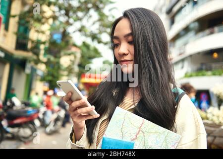 Asian woman with passport and paper map using mobile phone Stock Photo