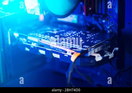 The contents of the computer inside - a video card, a cooler, and wires are illuminated with a bright blue light. Stock Photo