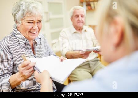 Cheerful senior woman and therapist in creative painting therapy with drawing pad Stock Photo