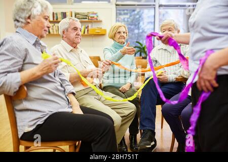 Seniors with dementia do an exercise with colorful ribbons for interaction Stock Photo
