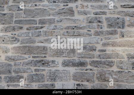 Textured natural wallpaper of hammered chiseled granite stone wall and grout in sunshine Stock Photo