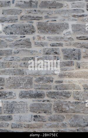 Textured natural wallpaper of hammered chiseled granite stone wall and grout in sunshine Stock Photo