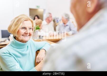 Smiling senior woman having small talk in retirement home or taking a break in the office Stock Photo