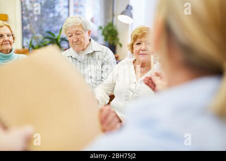 Female doctor and senior group in a therapy session with questionnaire in the old people's home Stock Photo