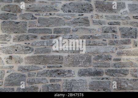 Textured natural wallpaper of hammered chiseled granite stone wall and grout in sunshine Stock Photo