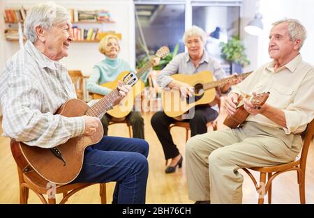 Seniors learn to play guitar together in a guitar course in the retirement home Stock Photo