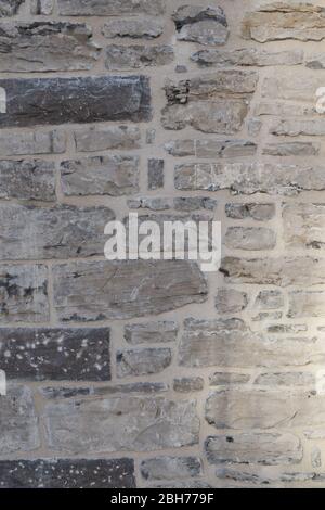 Textured natural wallpaper of hammered chiseled granite stone wall and grout in sunshine Stock Photo