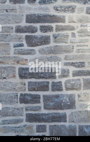 Textured natural wallpaper of hammered chiseled granite stone wall and grout in sunshine Stock Photo