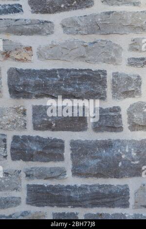 Textured natural wallpaper of hammered chiseled granite stone wall and grout in sunshine Stock Photo