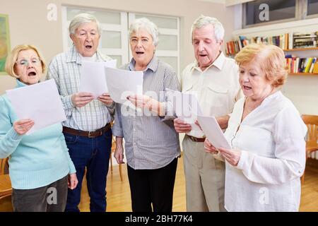 Old people as singers in a senior choir rehearsing in a retirement home Stock Photo