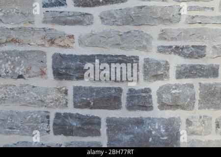 Textured natural wallpaper of hammered chiseled granite stone wall and grout in sunshine Stock Photo