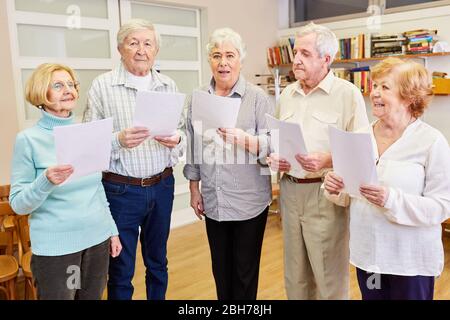 Group of seniors with dementia singing together in a choir rehearsal Stock Photo