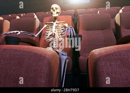 3D rendering of a skeleton in an empty movie theatre representing bored to death and stay at home concepts Stock Photo