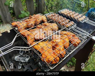 Grilled chicken wings and sausages on a grill Stock Photo
