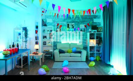 Room with nobody in it decorate for the party with neon light, beer and chips. Stock Photo