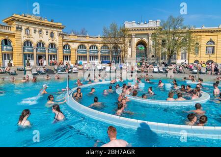 BUDAPEST - APRIL 3, 2019: Tourists and locals enjoy famous Szechenyi Baths on a beautiful spring day. This is a famous tourist attraction. Stock Photo