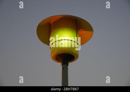 Street Lamp post with the evening skyline view. Outdoor light fixture with sky background. A single hooded street light. Stock Photo