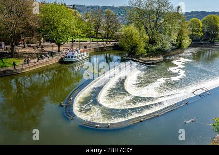 Tourist sightseeing cruise boat moored on the River Avon by Pulteney weir on a clear and sunny spring morning,  Bath, Somerset, England, UK Stock Photo