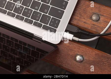 Laptop keyboard and two wires close-up on a bench Stock Photo