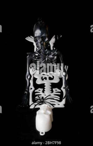 Top view of two skeleton toys making love, isolated on black background. Black and white, interracial relationship concept. Copy space Stock Photo