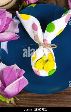 Small White Rabbit Figurine with White Easter Eggs and Pink Orchids and Blossoms on Rustic Wooden Background Stock Photo