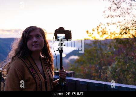 Mountains with young woman photographing timelapse in morning at new river gorge valley in Grandview Overlook, West Virginia during sunrise Stock Photo