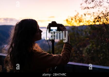 Fog clouds on mountains with woman photographing timelapse in morning at new river gorge valley in Grandview Overlook, West Virginia during sunrise Stock Photo