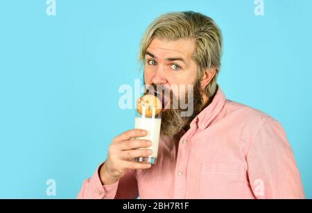 bearded man drink useful milk with pastry. The concept of healthy eating. Organic farm products for Breakfast or lunch. milk and cookies. happy farmer eat cookie dessert. Stock Photo