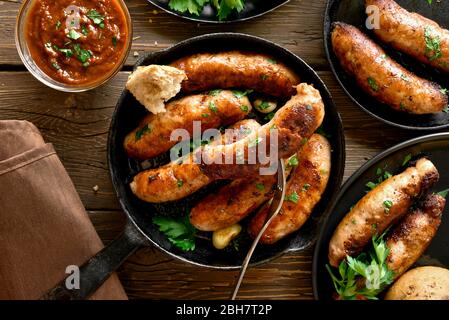 Close up of fried sausages in frying pan over wooden background. Top view, flat lay Stock Photo