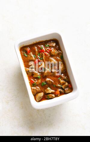 Peri-peri chicken livers in baking dish over light stone background with free text space. Stock Photo