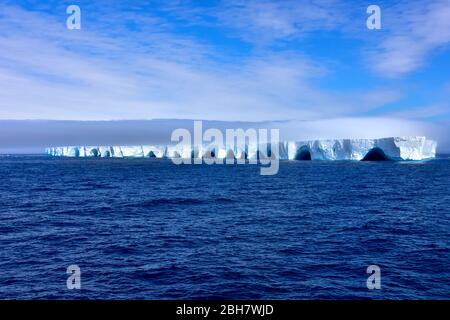 Blue Iceberg floating in Antarctica on a sunny day with blue sky. Stock Photo