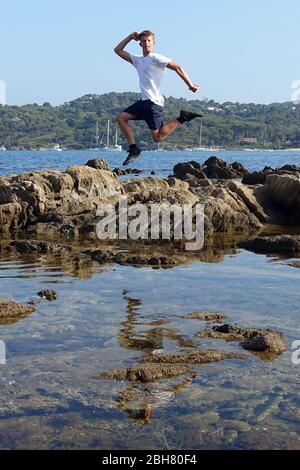 03.07.2019, Saint-Marcouf, Normandy, France - Boy jumps over a rock in the air. 00S190703D054CAROEX.JPG [MODEL RELEASE: YES, PROPERTY RELEASE: YES (c) Stock Photo