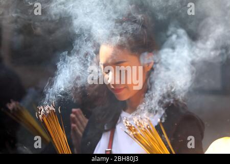 07.12.2019, Macao, , China - young woman praying with lit incense sticks in the A-Ma temple. 00S191207D210CAROEX.JPG [MODEL RELEASE: NO, PROPERTY RELE Stock Photo