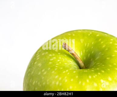 A close up of an organic green apple on a white background showing the stalk and waxed skin with copy space Stock Photo