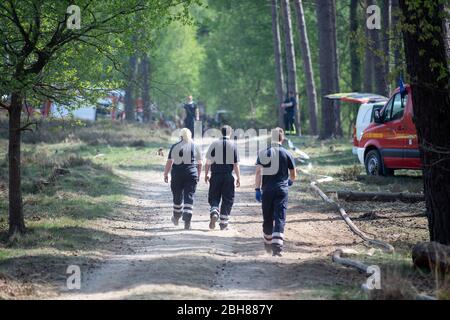 24 April 2020, North Rhine-Westphalia, Niederkrüchten: Firefighters walk through the forest to the scene. Several days after the outbreak of a large-scale forest fire in the German-Dutch border area, the fire brigade is still on site to fight embers' nests. Photo: Federico Gambarini/dpa Stock Photo