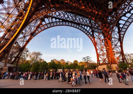 Tourists queuing under the base of the Eiffel Tower in Paris Stock Photo