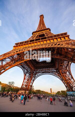 Tourists walking under the base of the Eiffel Tower in Paris Stock Photo
