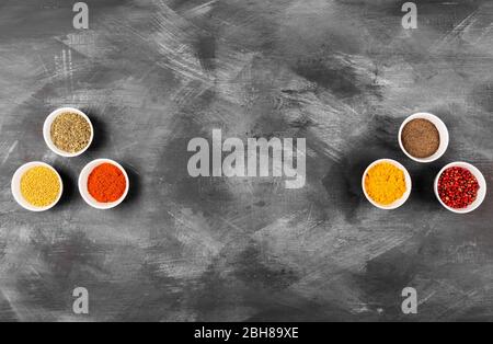 Various spices in white bowls on dark background. Top view, copy space Stock Photo