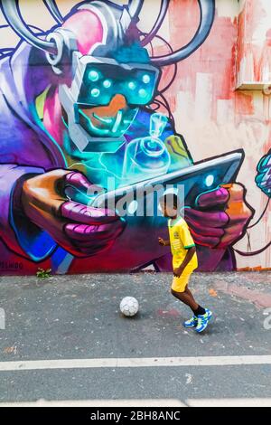 England, London, Shoreditch, Young Boy Playing Soccer in front of Street Art Stock Photo