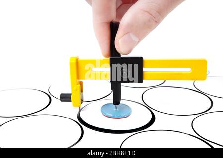 Female hand cuts paper circles with a rotary compass cutter. Close-up shot, front view. Stock Photo