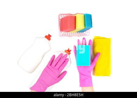 Cleaning supplies isolated on white: a small shopping basket with dishwashing sponges, yellow cleaning cloth, two plastic bottles with detergent. Stock Photo