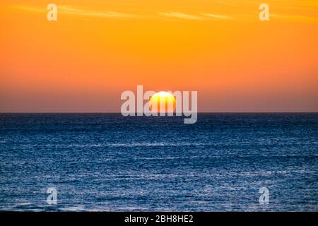 Perfect sunset moment when the sun touch the water in the middle of the ocean in summer vacation tropical island - romantic and beautiful natural outdoor background for vacation concept Stock Photo