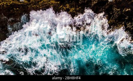 Aerial view to ocean waves. Blue water background - top vertical view of coastline and big power waves on the rocks - splash and dangerous concept for nature outdoor beauty Stock Photo